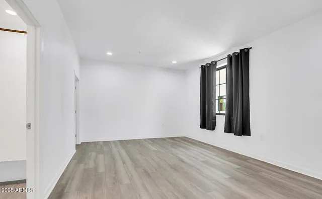 a view of an empty room with wooden floor & closet