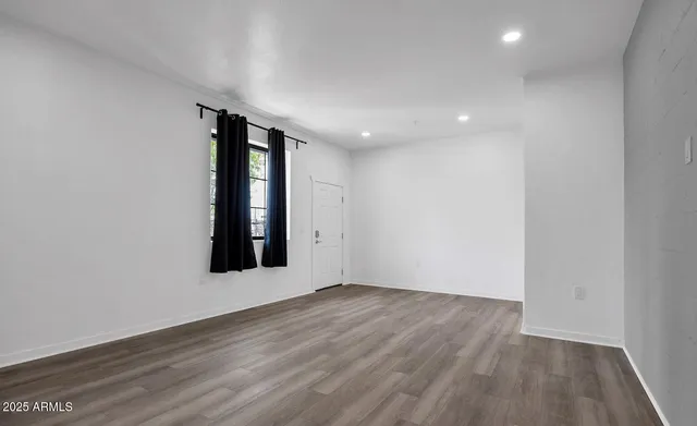 a view of an empty room with wooden floor and closet