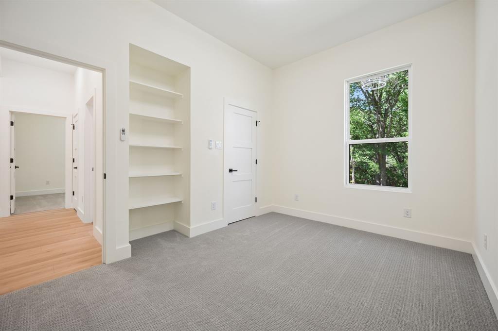 105 Buckboard Trail Oak Point, TX 75068 - Photo 17 of 27 First floor bedroom featuring light carpet and a bookcase.
