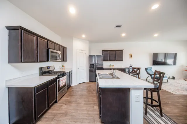 a large kitchen with stainless steel appliances a sink stove and refrigerator