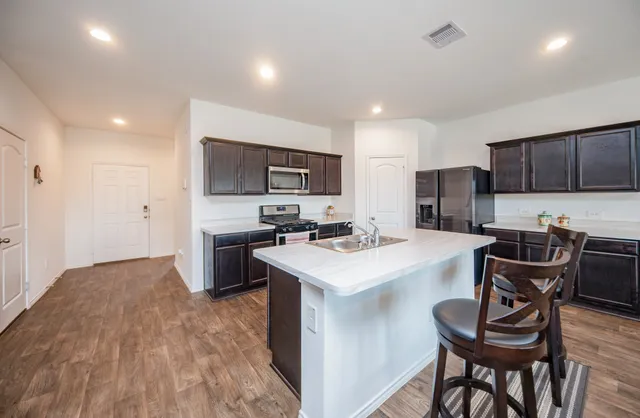 a kitchen with a dining table chairs and refrigerator