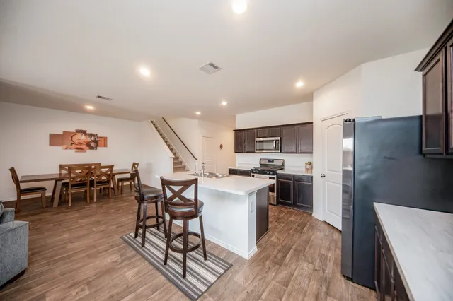 a kitchen with stainless steel appliances a dining table chairs stove and refrigerator