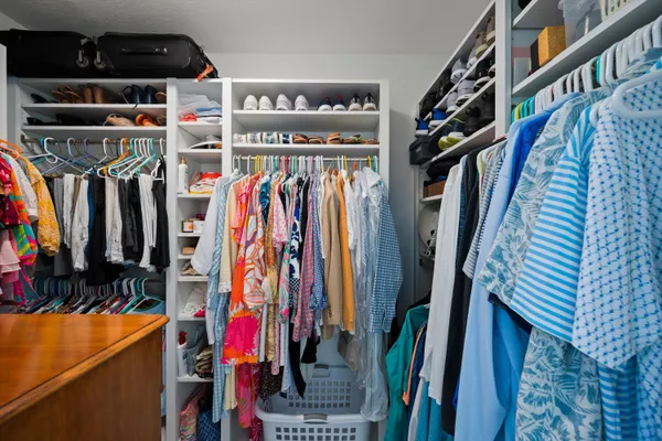 a view of walk in closet with clothes and shoes
