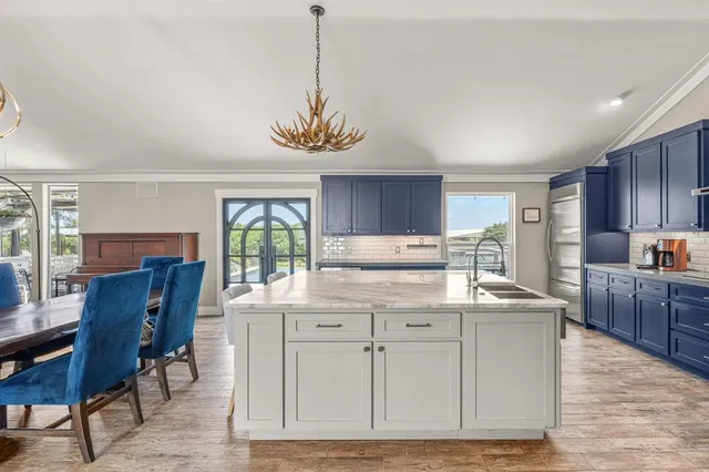 a kitchen with stainless steel appliances granite countertop a stove a sink a dining table and chairs with wooden floor