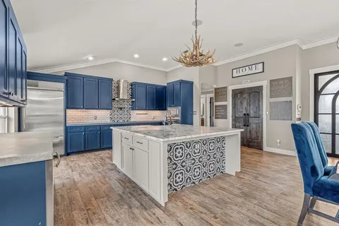 a kitchen with stainless steel appliances granite countertop a stove a sink dishwasher a refrigerator and a dining table with wooden floor