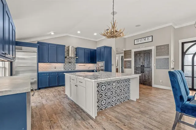 a kitchen with stainless steel appliances granite countertop a stove a sink dishwasher a refrigerator and a dining table with wooden floor