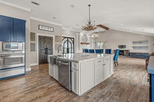 a kitchen with stainless steel appliances granite countertop a lot of counter top space and wooden floor