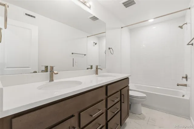 a bathroom with a granite countertop sink a toilet and shower