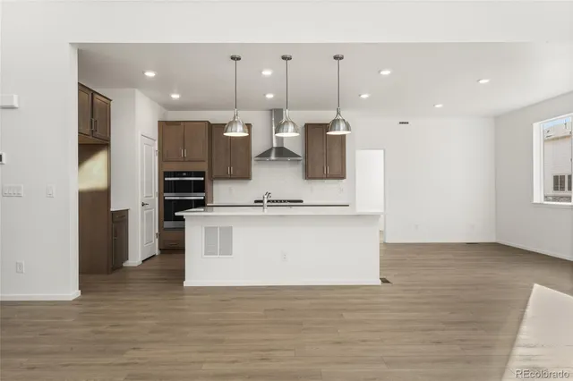 a view of kitchen with stainless steel appliances kitchen island a stove a refrigerator a oven and a view of living room