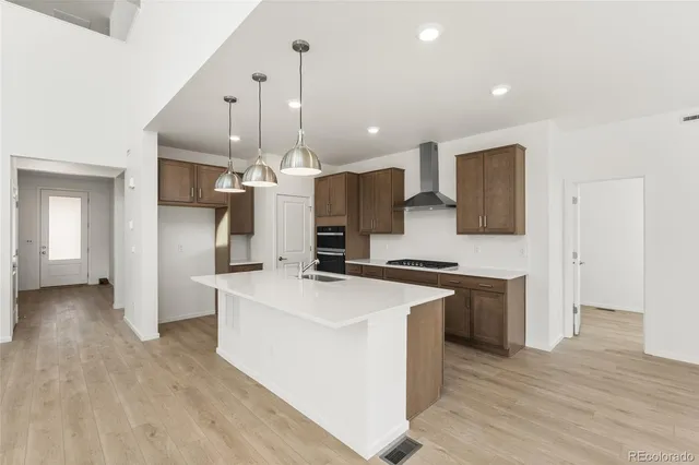 a large kitchen with stainless steel appliances a large center island a stove a refrigerator and a view of living room