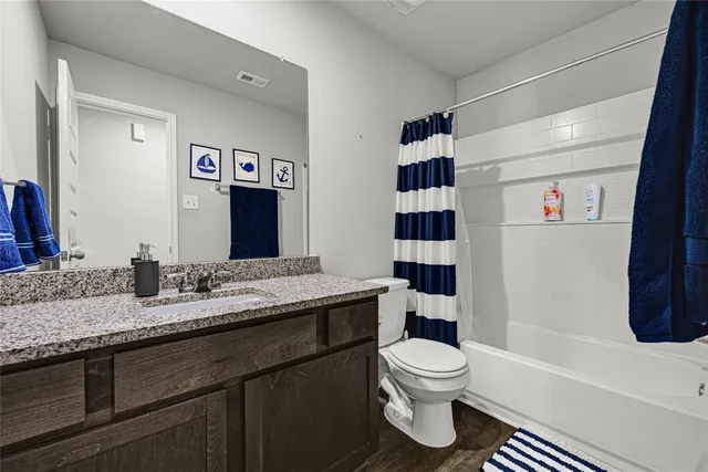 a bathroom with a granite countertop sink toilet a shower and a mirror
