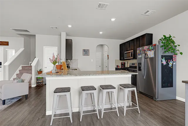 a kitchen with stainless steel appliances a dining table chairs refrigerator and sink