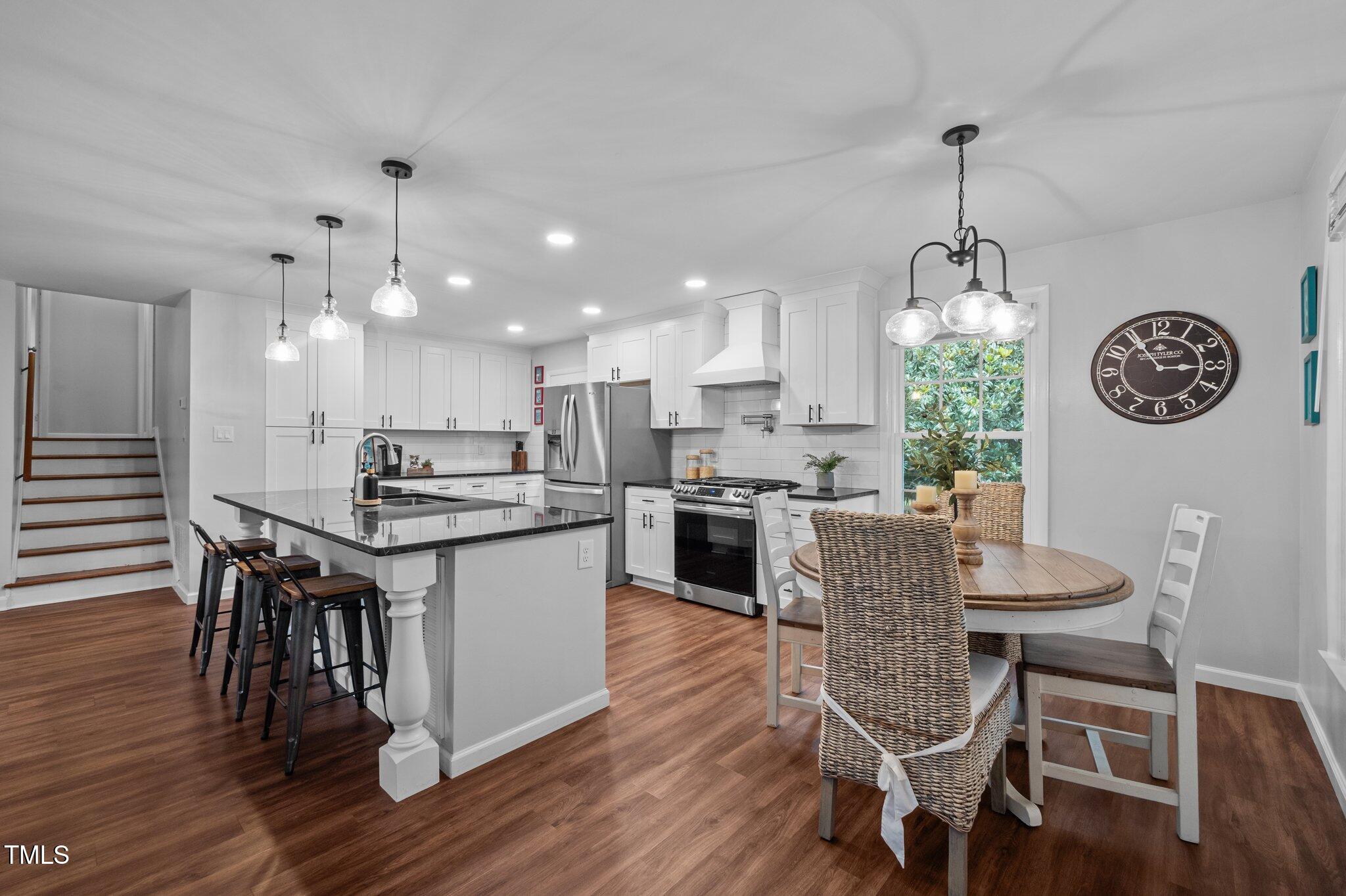 1205 Willow Drive Chapel Hill, NC 27517 - Photo 4 of 45 a kitchen with stainless steel appliances kitchen island granite countertop a wooden table chairs and white cabinets