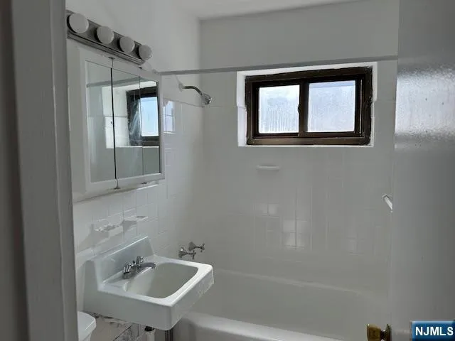 a bathroom with a sink mirror and a bathtub