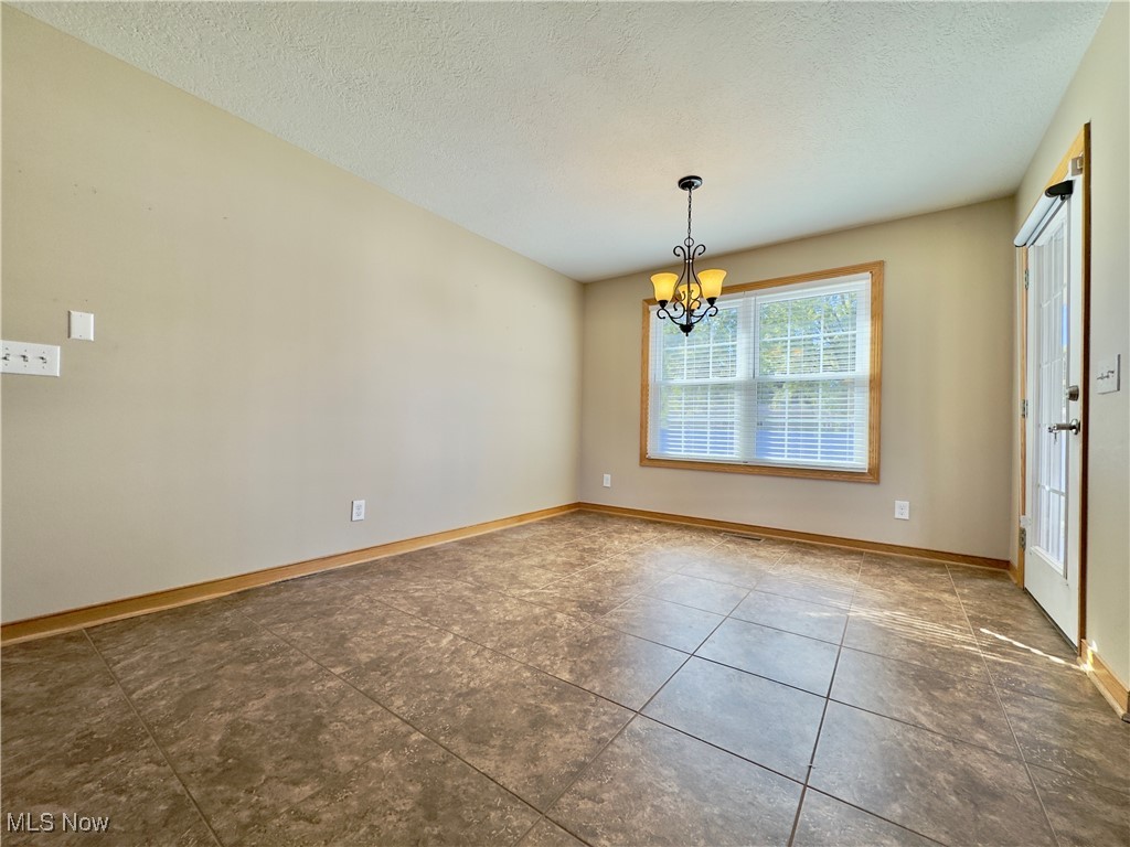 6014 Wentworth Road Southwest Canton, OH 44706 - Photo 6 of 22 Unfurnished dining area featuring tile flooring and a chandelier