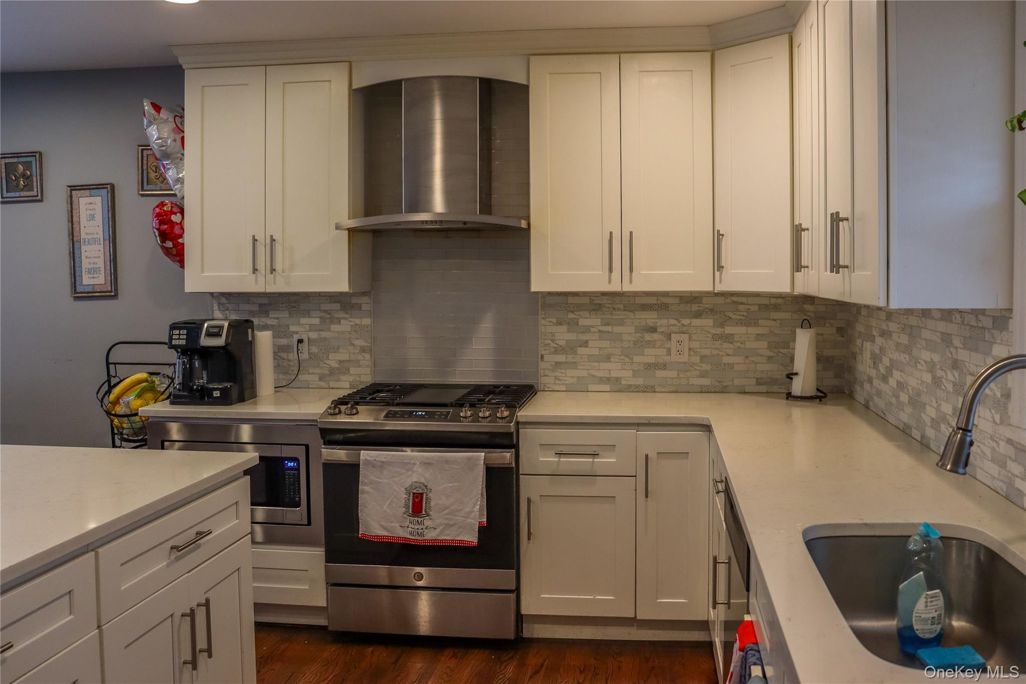 29 Oak Street Islip, NY 11751 - Photo 4 of 15 Kitchen featuring wall chimney range hood, appliances with stainless steel finishes, tasteful backsplash, and white cabinets
