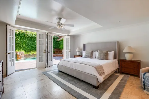 a spacious bedroom with a large bed and a chandelier fan