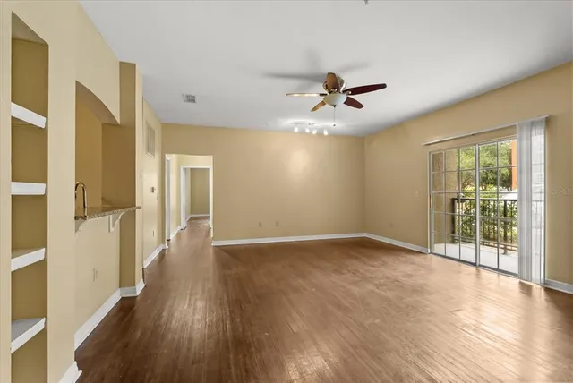 a view of an empty room with wooden floor and a window