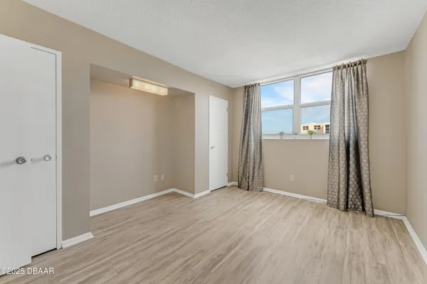 a view of an empty room with wooden floor and a window