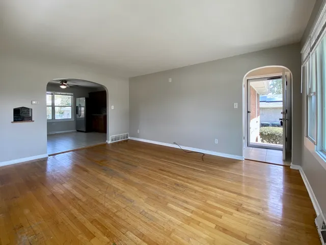 an empty room with wooden floor and windows