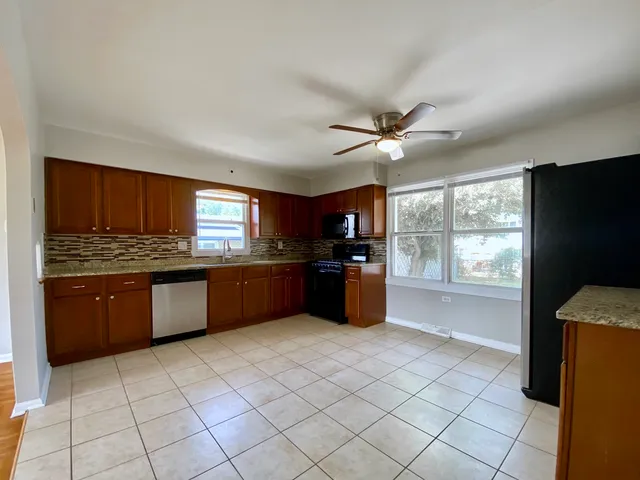 a kitchen with stainless steel appliances kitchen island granite countertop a refrigerator and a sink