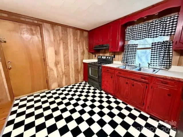 a kitchen with a sink a stove cabinets and a wooden floor