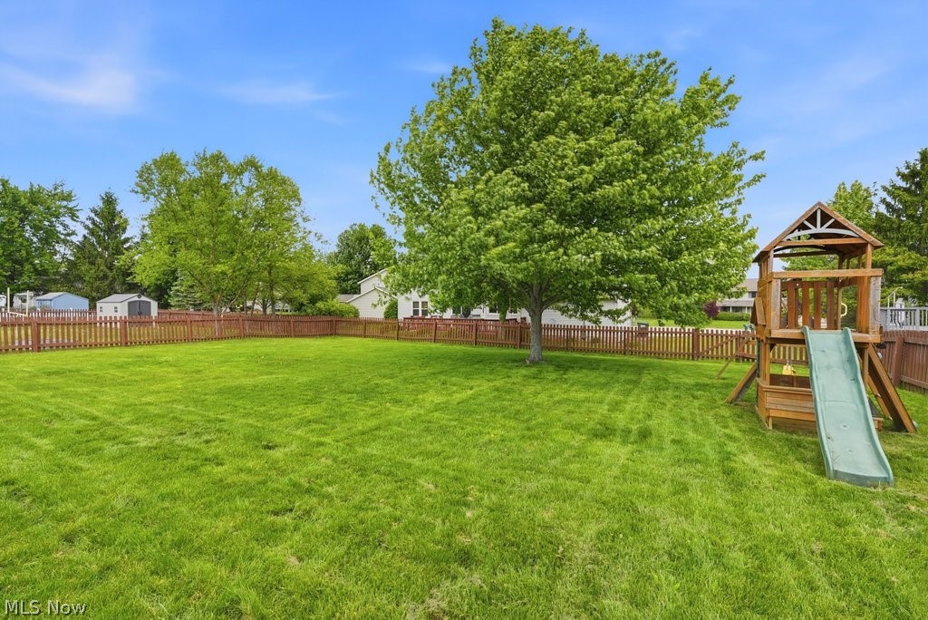 5321 Young Road Stow, OH 44224 - Photo 4 of 37 Expansive fenced backyard featuring a substantial tree and a wooden playset with a slide