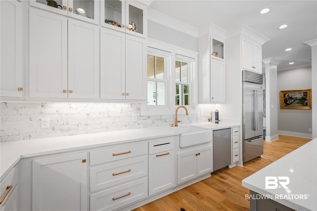 707 Cardamel Court Fairhope, AL 36532 - Photo 11 of 40 Kitchen with white cabinetry, crown molding, light wood-type flooring, appliances with stainless steel finishes, and backsplash