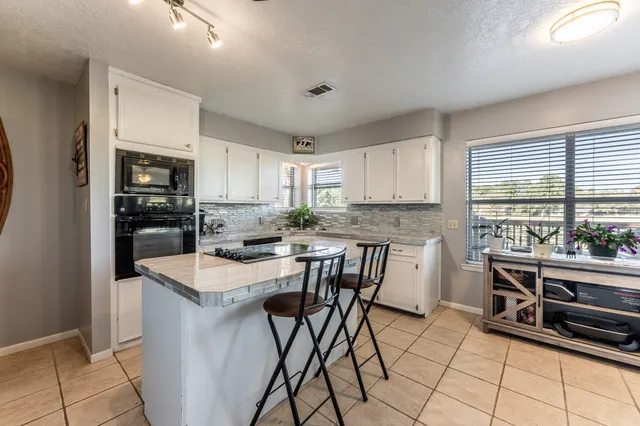 a kitchen with stainless steel appliances granite countertop a stove top oven a sink a dining table and chairs