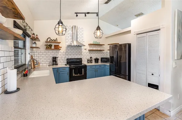 a kitchen with stainless steel appliances kitchen island granite countertop a refrigerator a sink dishwasher and a stove