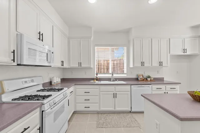 a kitchen with a sink dishwasher stove and white cabinets with wooden floor