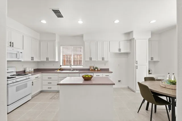 a kitchen with a refrigerator a stove a dining table and chairs