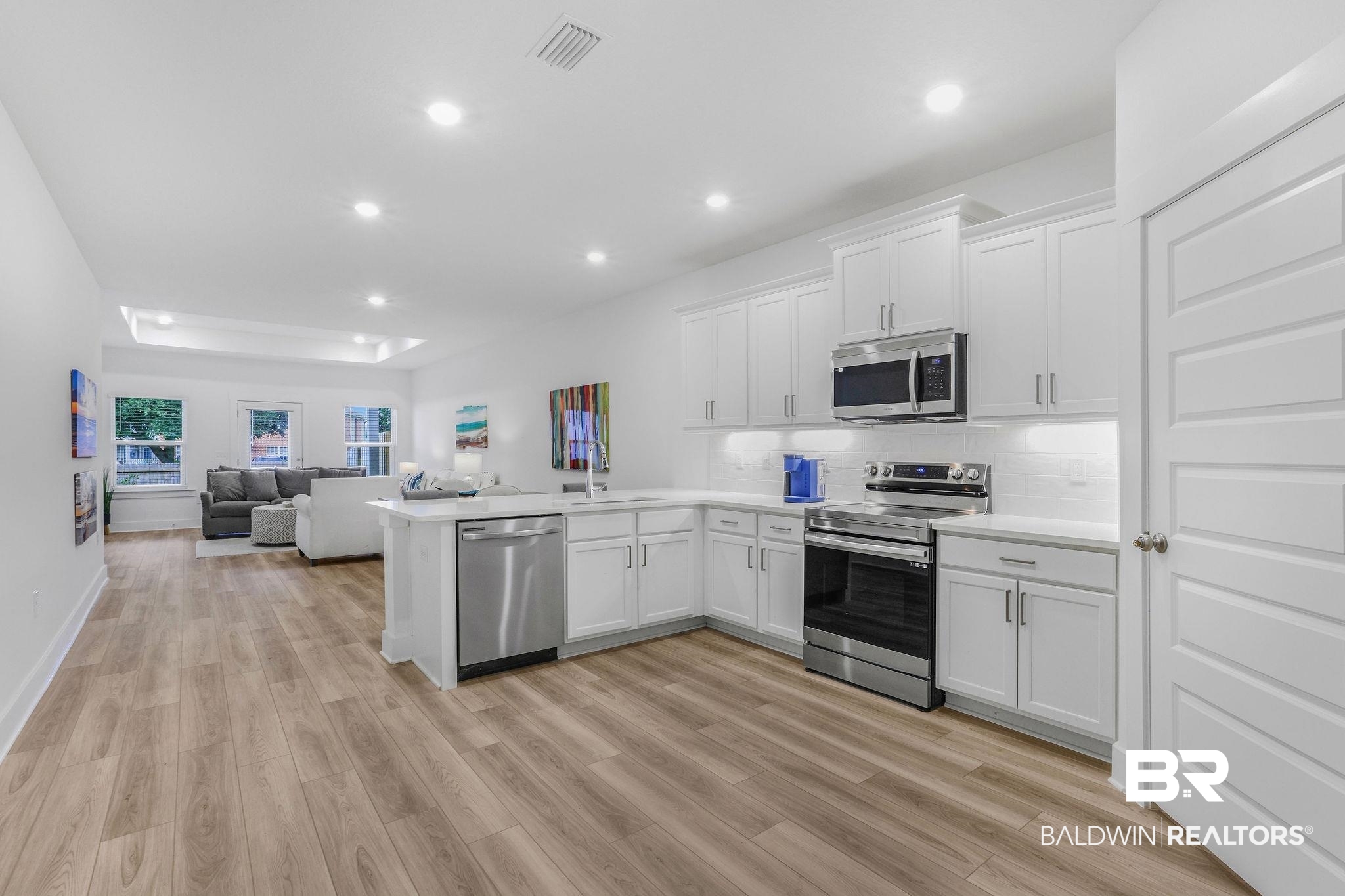 9859 Willet Way Foley, AL 36535 - Photo 23 of 23 Kitchen featuring white cabinetry, stainless steel appliances, open floor plan, a peninsula, and light wood-style flooring