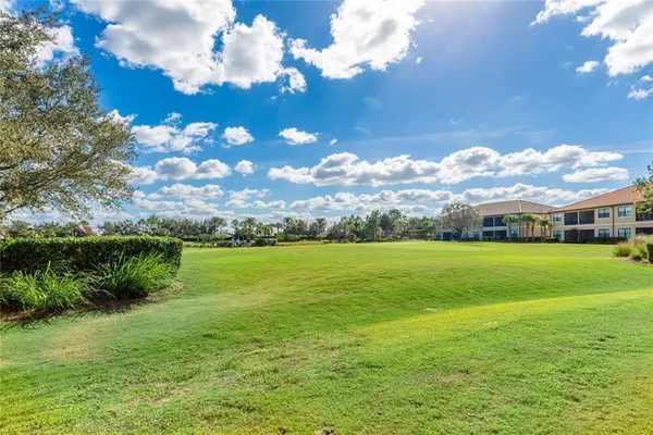 an empty room with a ceiling fan and kitchen view