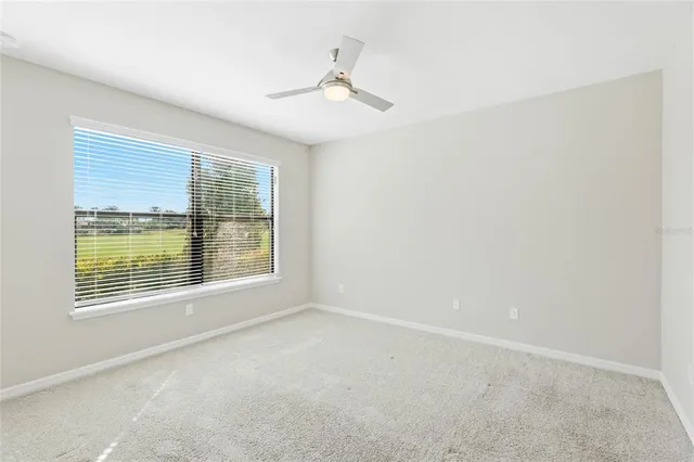 an empty room with a ceiling fan and a window