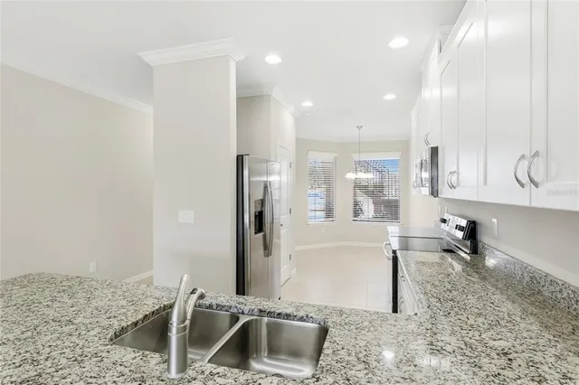 a kitchen with stainless steel appliances granite countertop a sink refrigerator and cabinets