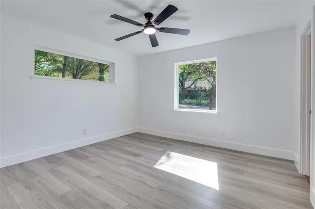 a view of empty room with wooden floor and fan
