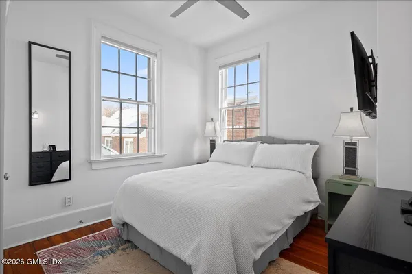a bedroom with a bed a flat tv screen and a window