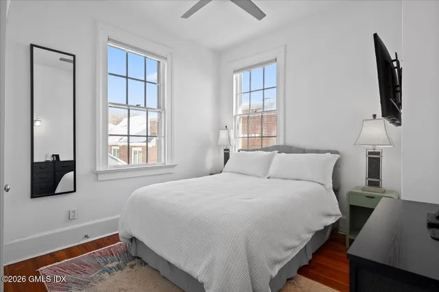 a bedroom with a bed a flat tv screen and a window