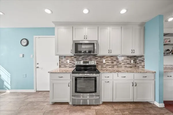 a kitchen with white cabinets and a stove with wooden floor