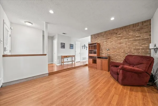 a living room with stainless steel appliances furniture and a wooden floor