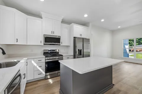 a kitchen with stainless steel appliances granite countertop a sink a stove a refrigerator and a window