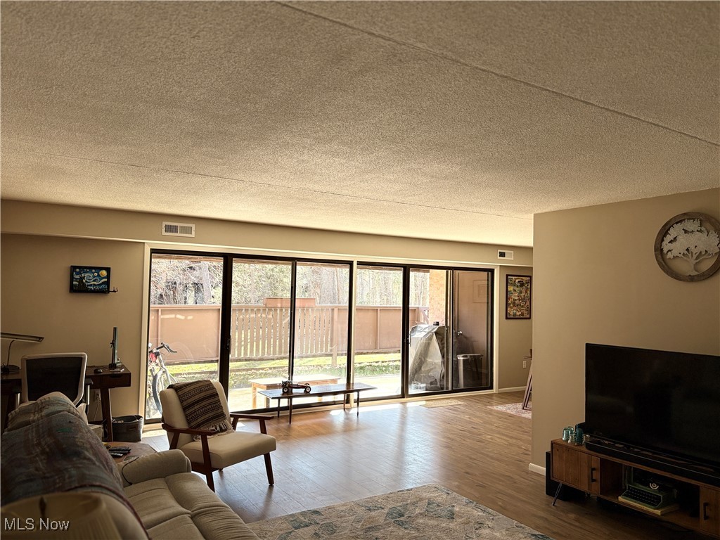 935 Canyon View Road, Unit 104 Northfield, OH 44067 - Photo 5 of 46 Living area with visible vents, a textured ceiling, baseboards, and wood finished floors