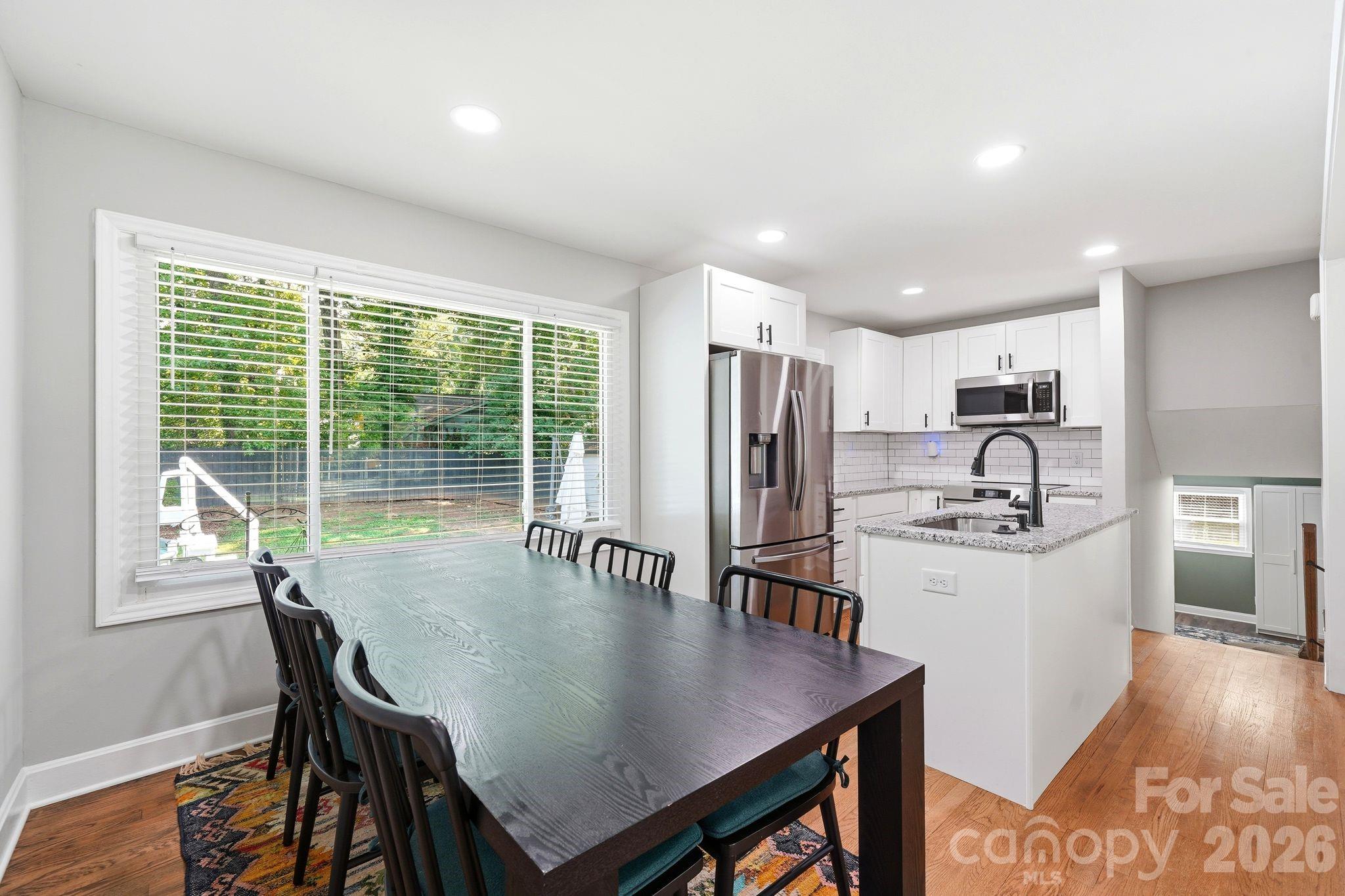 7552 Idlewild Road Charlotte, NC 28212 - Photo 36 of 40 a kitchen with stainless steel appliances granite countertop a stove a refrigerator a sink a dining table and chairs