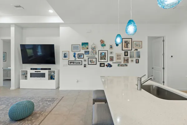 a living room with stainless steel appliances kitchen island granite countertop a couch and a flat screen tv
