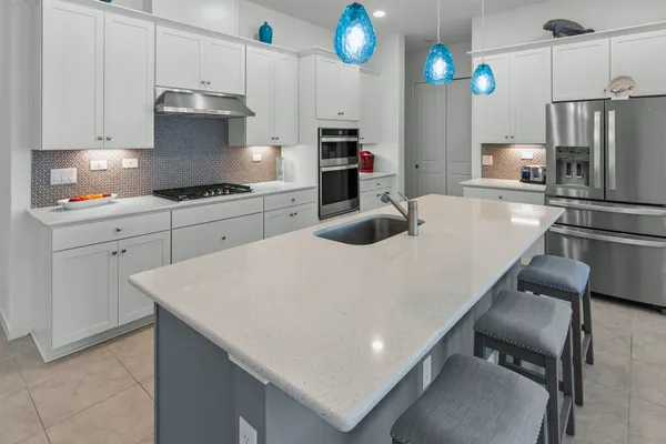 a kitchen with kitchen island a stove a sink and a refrigerator
