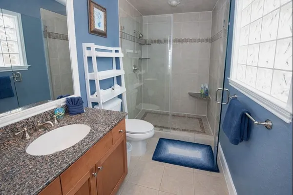 a bathroom with a granite countertop sink toilet a mirror and shower