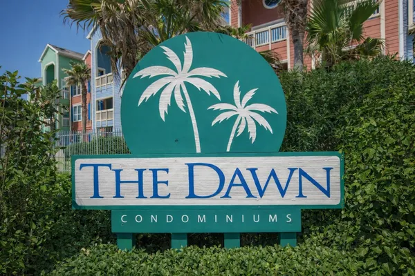 a view of sign board with buildings and trees