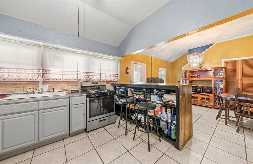 2805 Parrott Avenue Waco, TX 76707 - Photo 7 of 19 Kitchen with stainless steel range with gas cooktop, vaulted ceiling, gray cabinets, light tile patterned floors, and hanging light fixtures