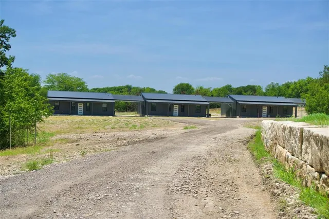 a front view of house with yard and trees in the background